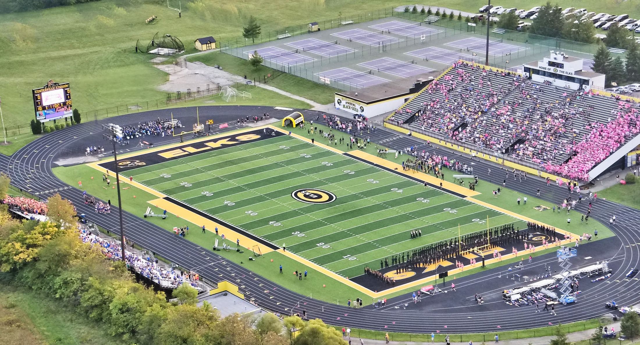 A packed stadium on game day lit by a Major Display scoreboard