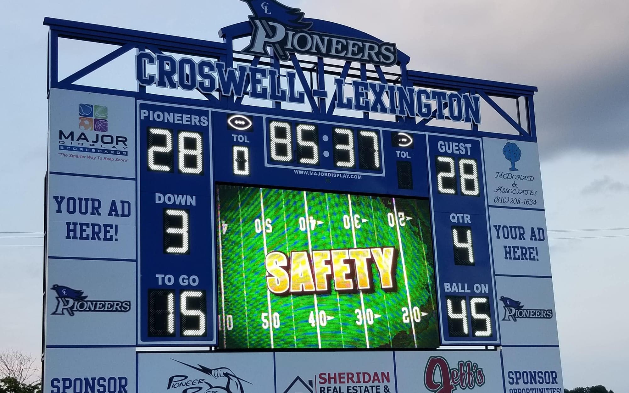 A finished Croswell-Lexington football scoreboard: LED score, clock, and down readouts around a full-color video panel
