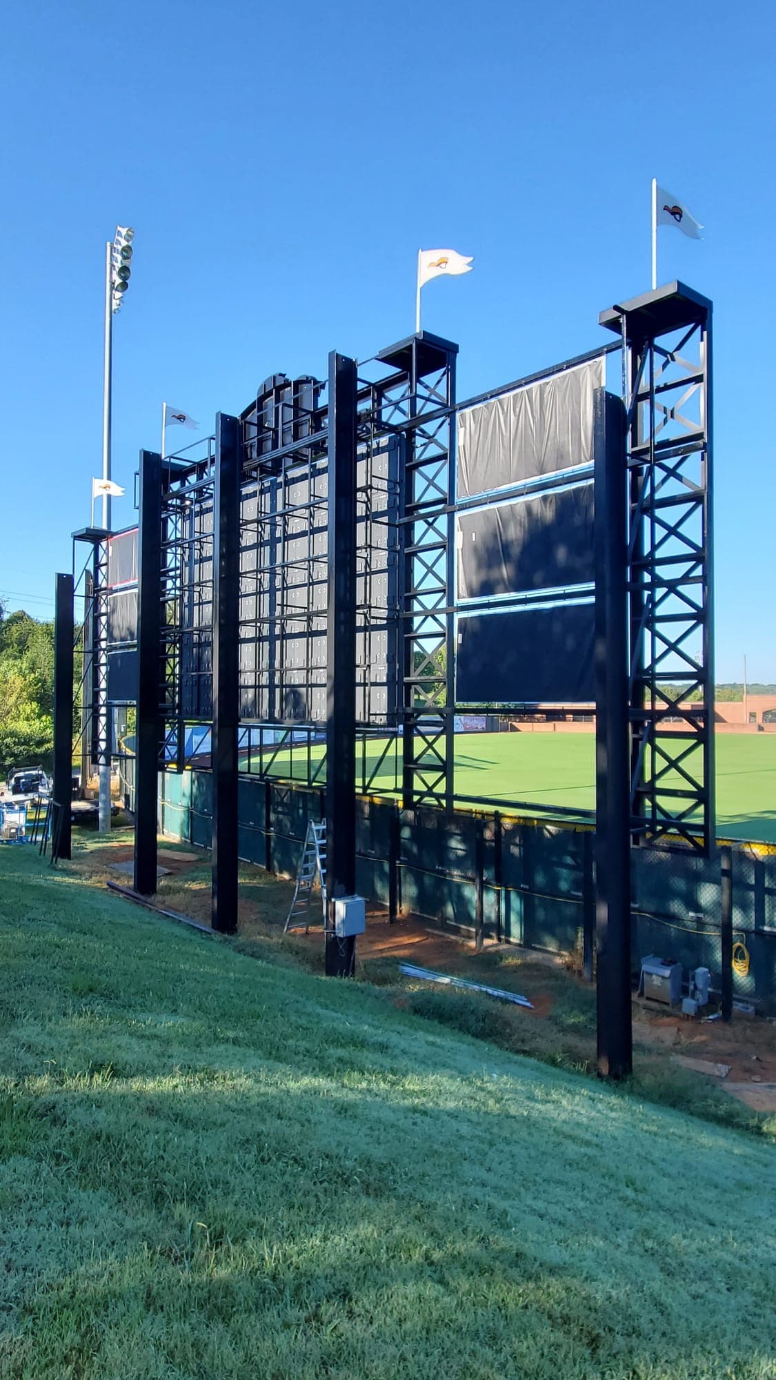 The engineered steel structure behind a ballpark scoreboard, seen from the outfield hillside