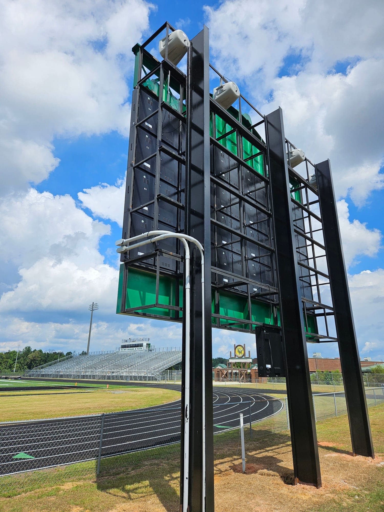 Behind a stadium video board: the steel structure, cabinet framing, and speakers beside the track